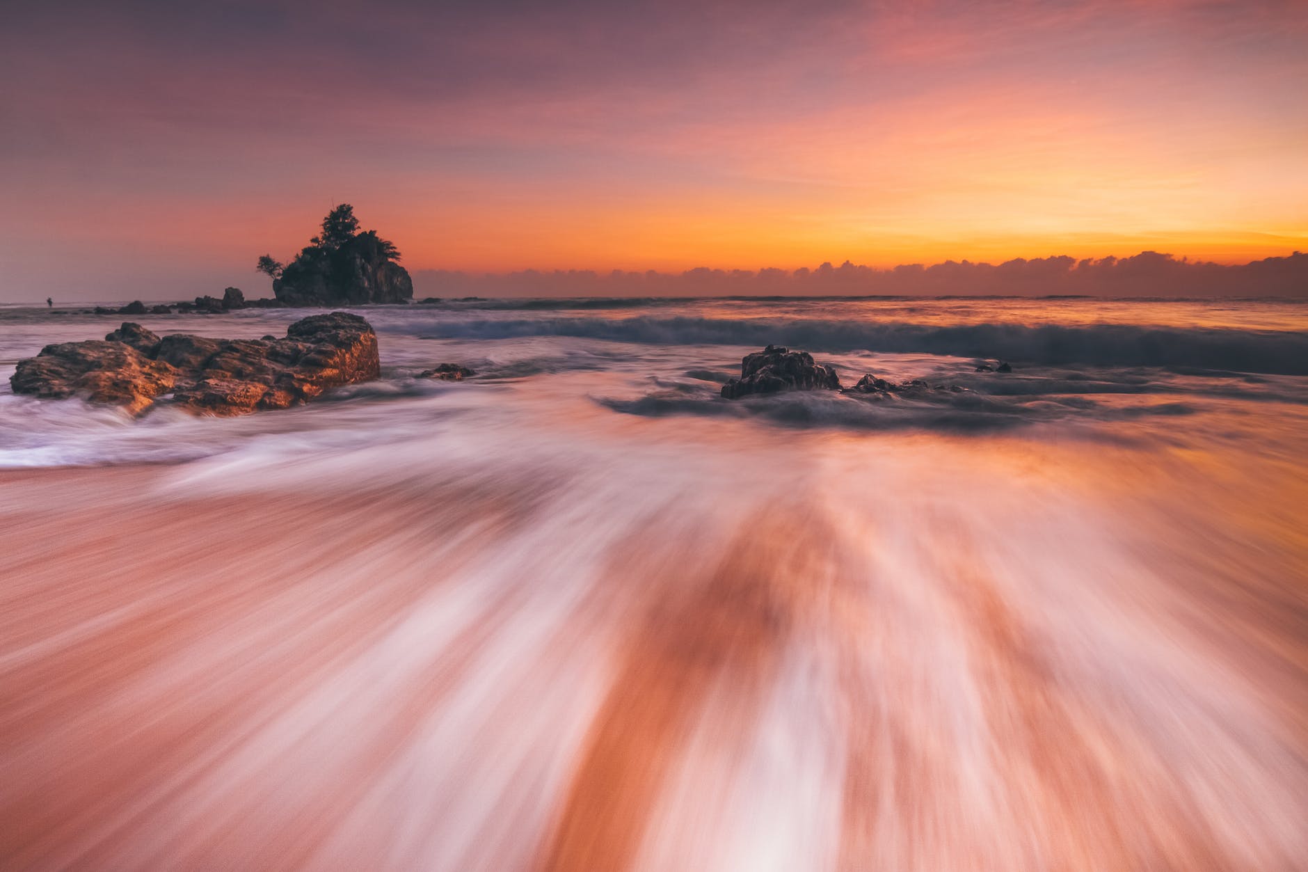 stormy sea with fast water flow on beach at sunset